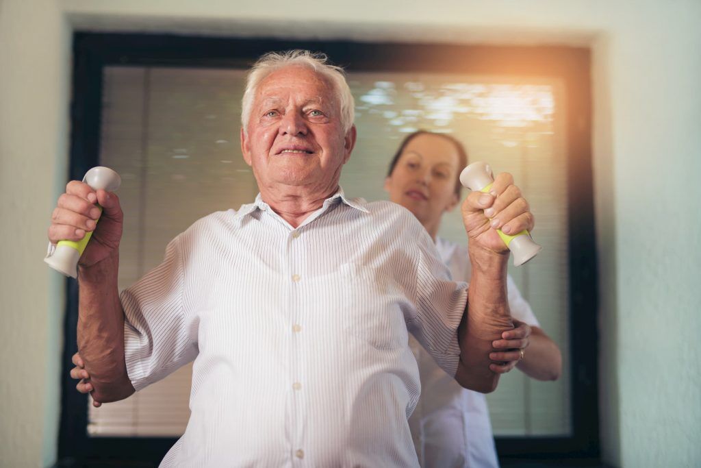 elderly white man lifting weights with nurse therapist