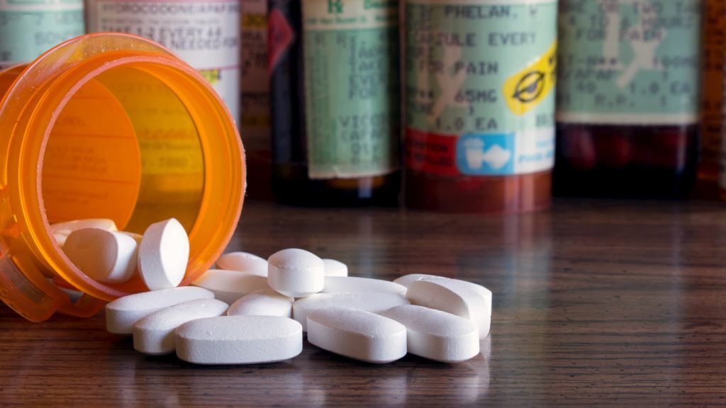 orange bottle of pain killers pain medicine opioids with other bottles of pain killers in the background spilled on the table to show pain management medication opioid safety